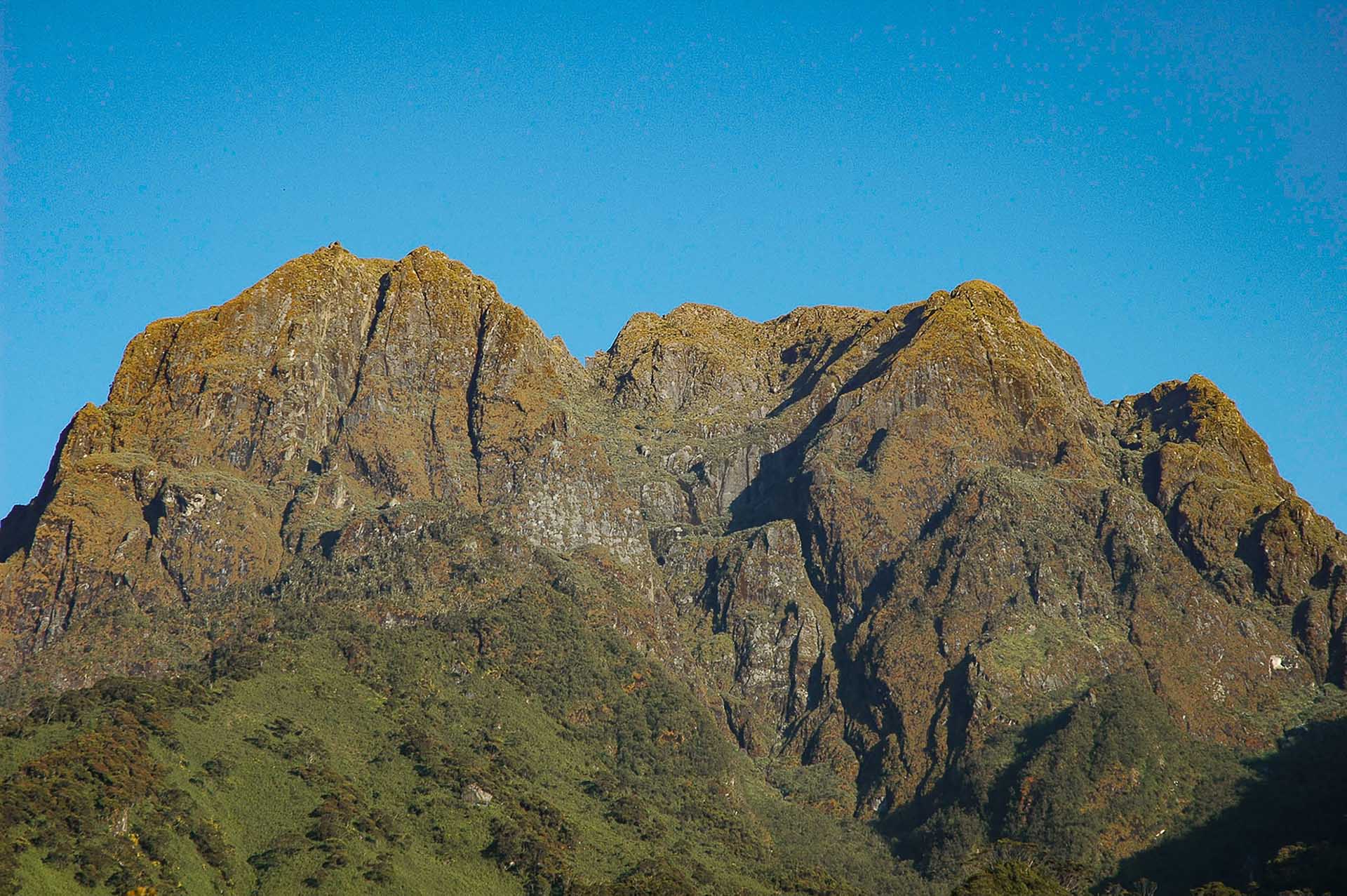 Majestuosas e intemporales, las cumbres de las montañas Rwenzori surcan los cielos, siendo testigos silenciosos de eones de cambio mientras acunan secretos ancestrales en su elevado abrazo.